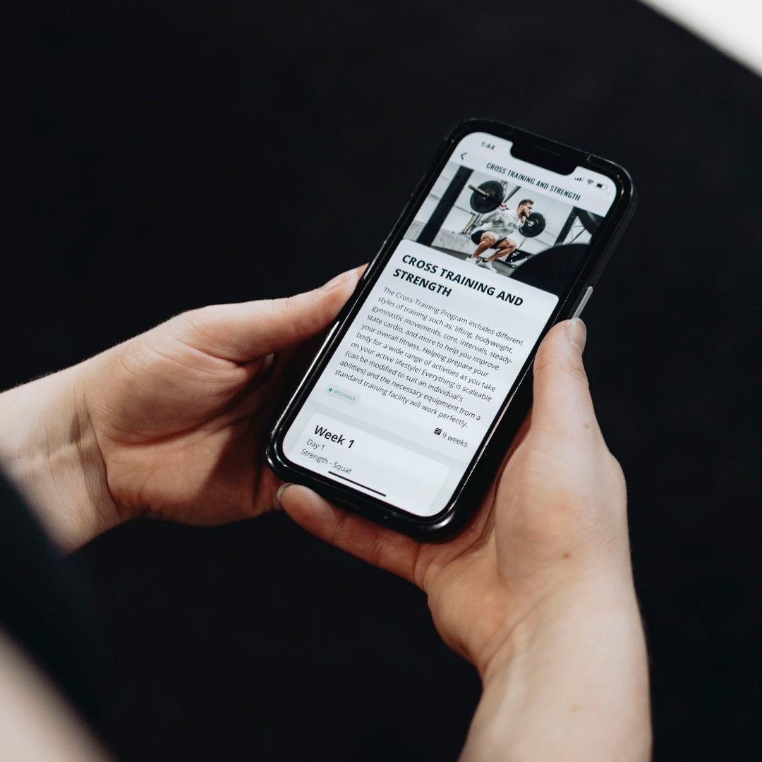 Person holding a smartphone displaying a cross-training and strength workout plan.