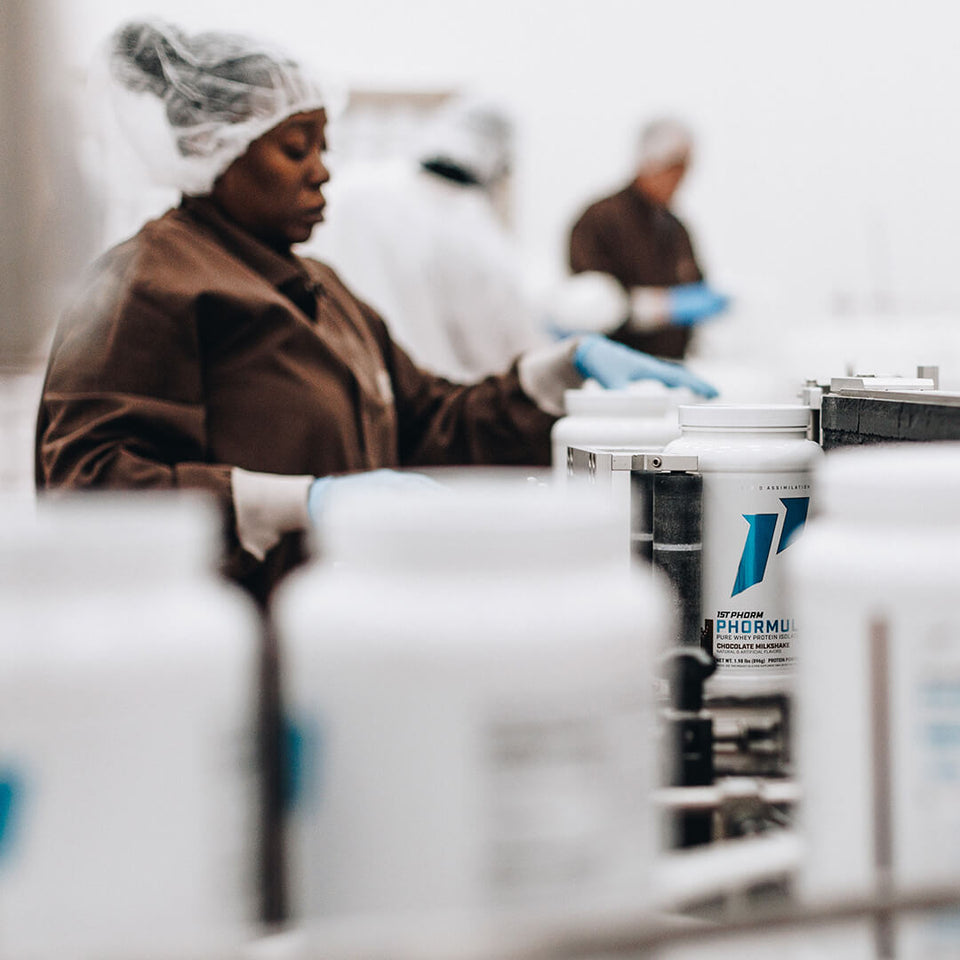 woman works on manufacturing line with protein powder bottles