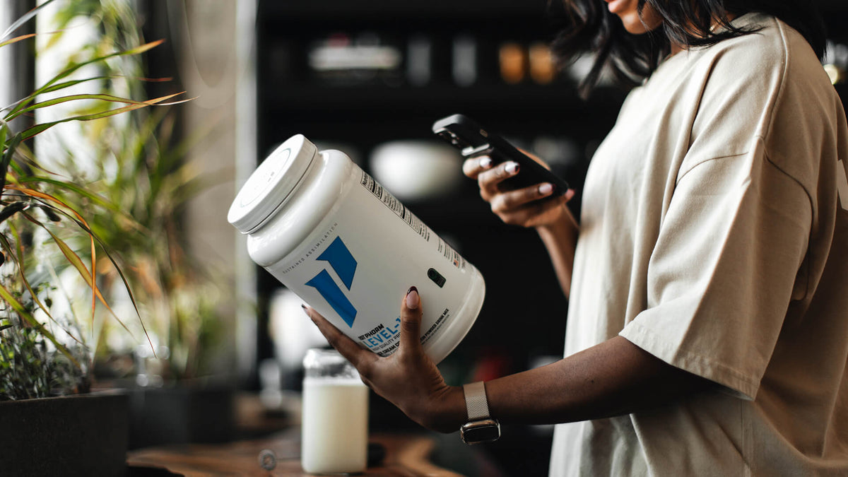 woman reads nutrition label on 1st Phorm protein tub.